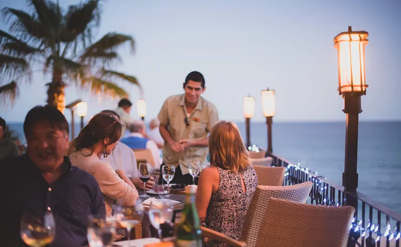 Guests at dinner beside the ocean at dusk