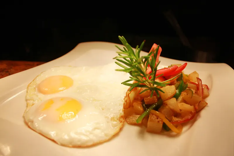 Sunny-side-up eggs with sautéed potatoes, peppers and rosemary