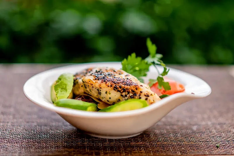 Grilled fish over avocado in a white bowl