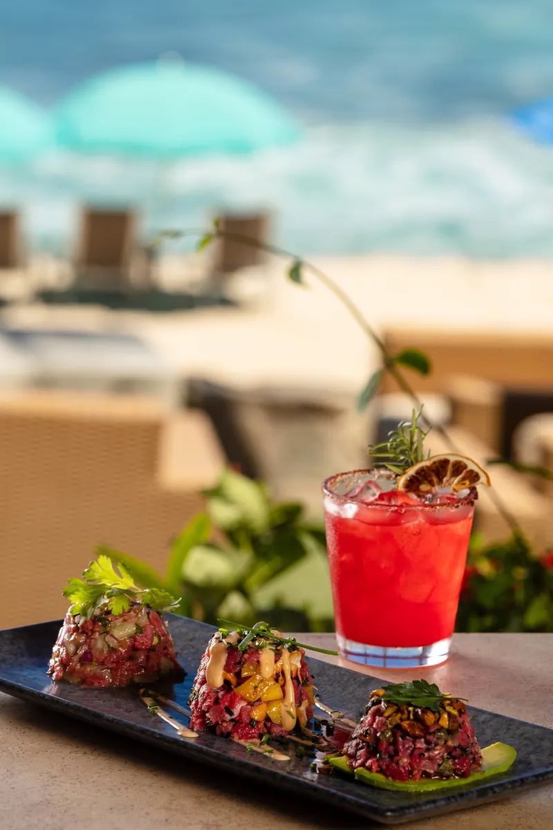 Tuna tartare and a red cocktail on a sunny table